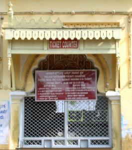 mysore-palace-ticket-counter Ticket counter at Mysore Palace. Note the signboard with Palace opening timings and ticket costs.